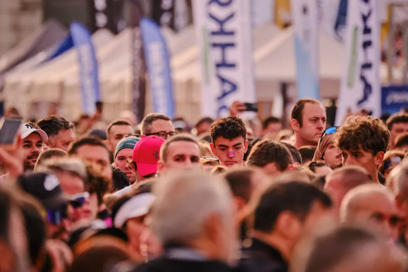 A dense crowd beneath event flags in the city centre.