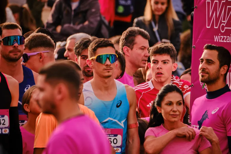 A runner in a turquoise vest and mirrored sunglasses among participants.