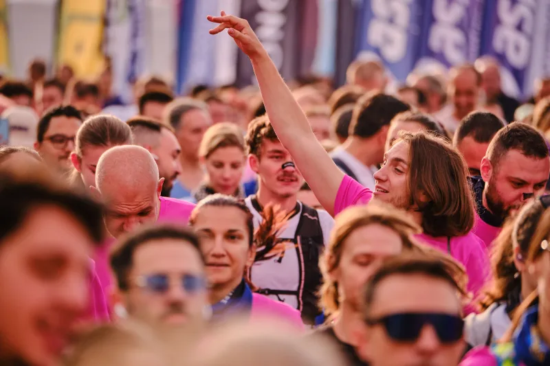 A woman raising an arm above the crowd of runners.