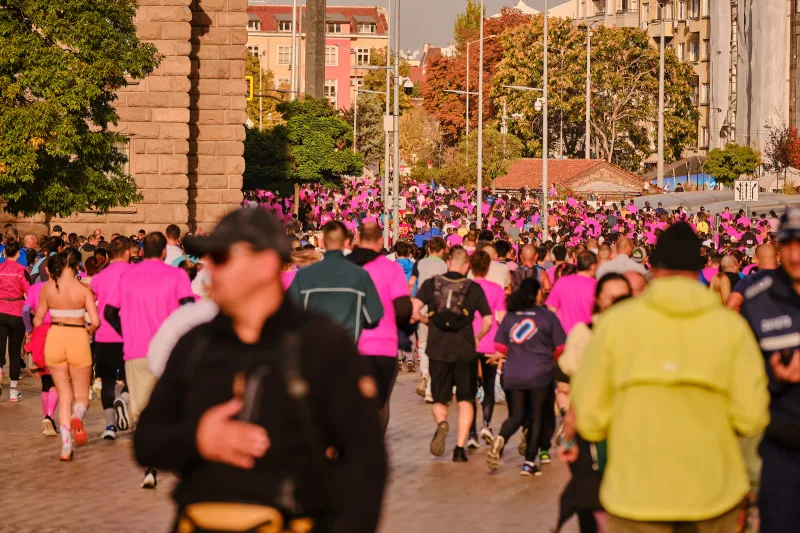 Participants crossing the sunlit square between large stone buildings.