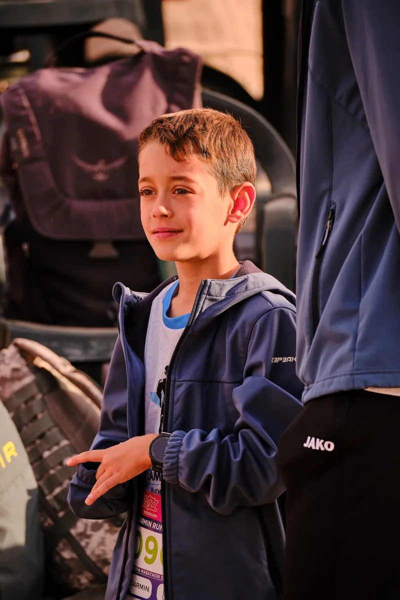 A young spectator in a blue jacket beside the event area.