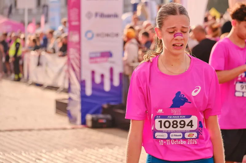 A smiling woman in a pink event shirt and glasses.