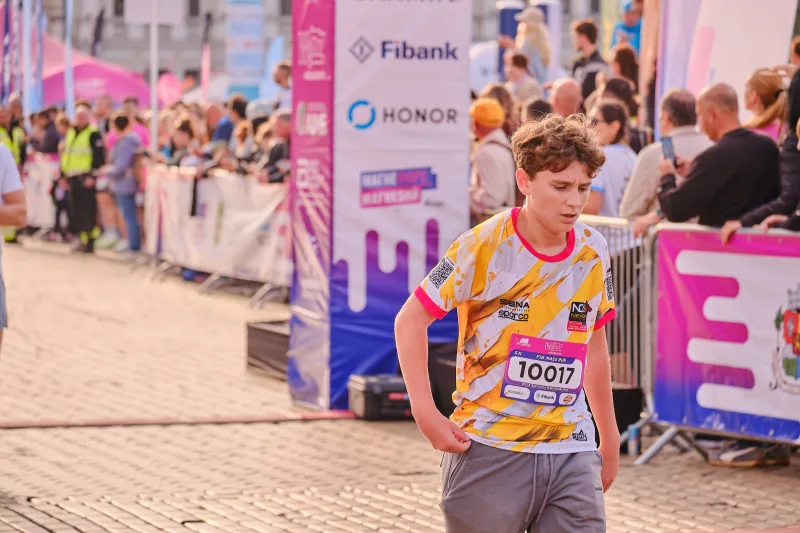 A young participant in a brightly patterned jersey near the barriers.