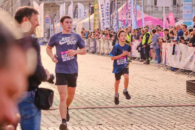 Two runners approaching along the sunlit cobbled route.