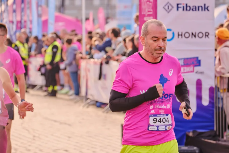 A runner in a pink shirt and bright green shorts moving through the square.