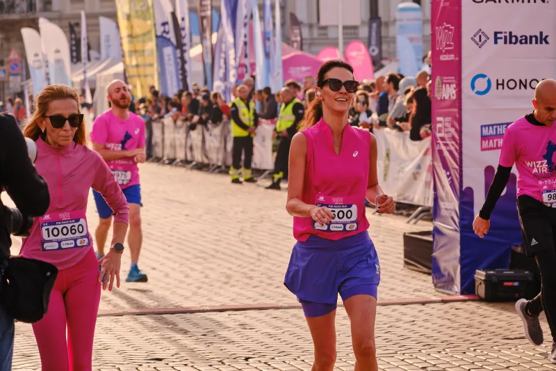 A runner in a pink vest, blue shorts and a cap approaching the camera.