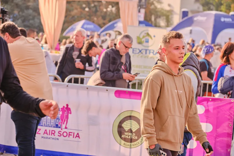 A young spectator in a tan hoodie beside the race barriers.