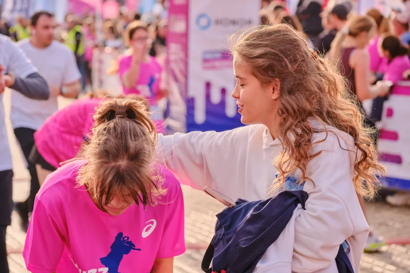 A woman putting an arm around a participant in a pink shirt.