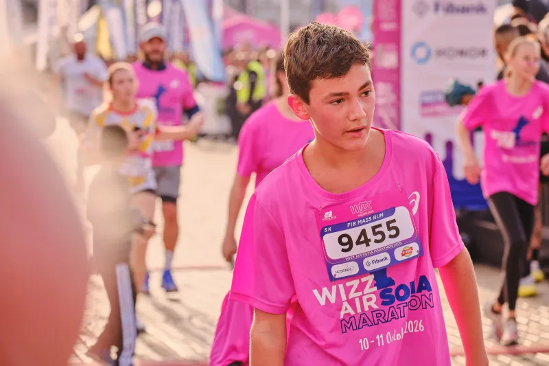 A young participant in a pink event shirt looking to the side.