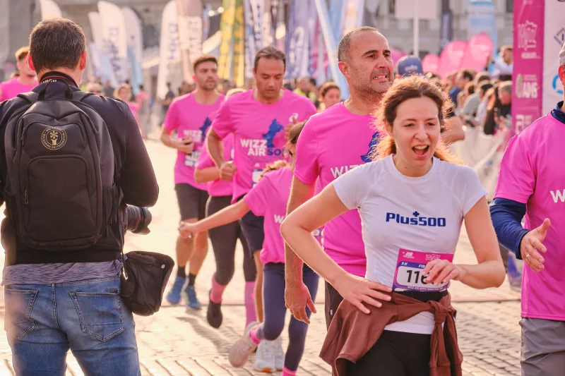 A smiling runner in a pale top resting with hands on hips.