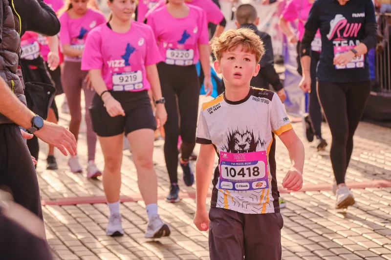 A young runner in a pale patterned shirt approaching through the crowd.