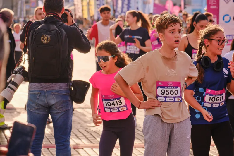 A young runner in a tan shirt looking across the crowd.