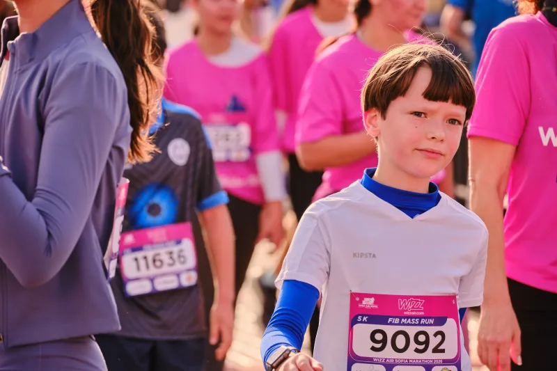 A young participant in a white shirt with blue trim in the crowd.