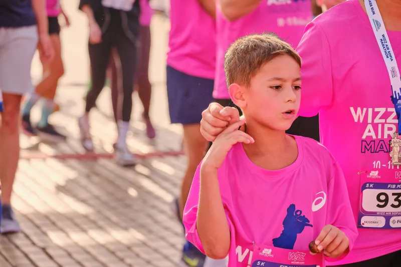 A young participant in pink raising a hand beside the crowd.