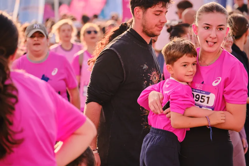 A woman in pink holding a young participant in her arms.