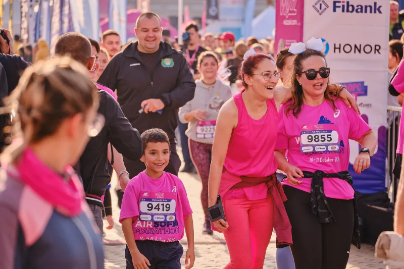 Two women and a young participant walking together through the crowd.