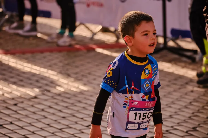 A young participant in a blue-and-yellow sports jersey in sunlight.