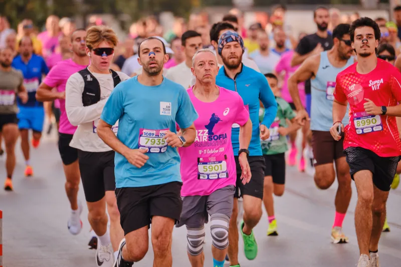 Runners in turquoise and pink leading a busy group down the street.