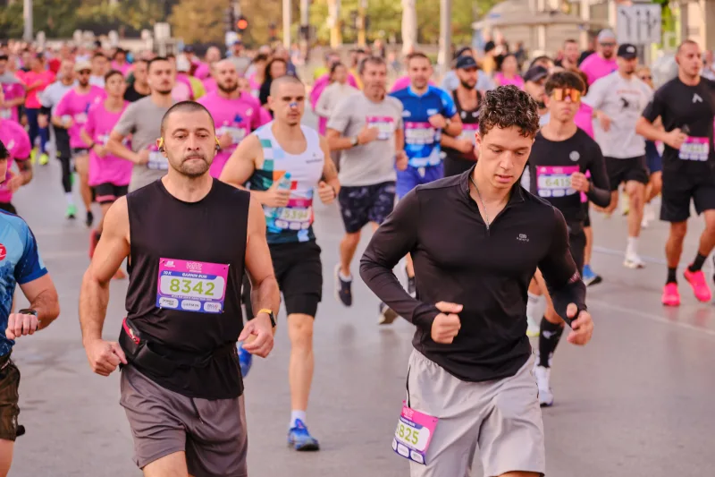 Two runners in black moving side by side along the road.