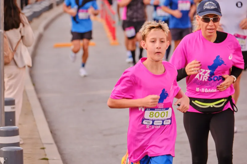 A young participant and a runner in a cap wearing matching pink shirts.