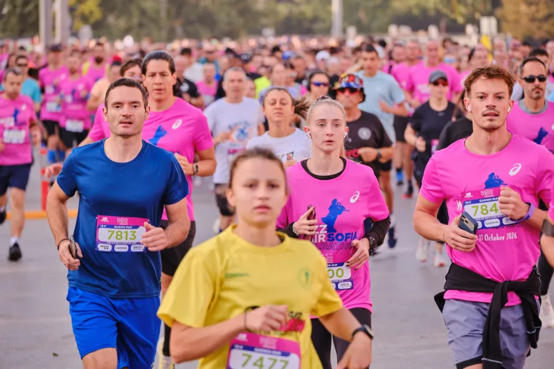 A young runner in yellow approaching ahead of participants in blue and pink.