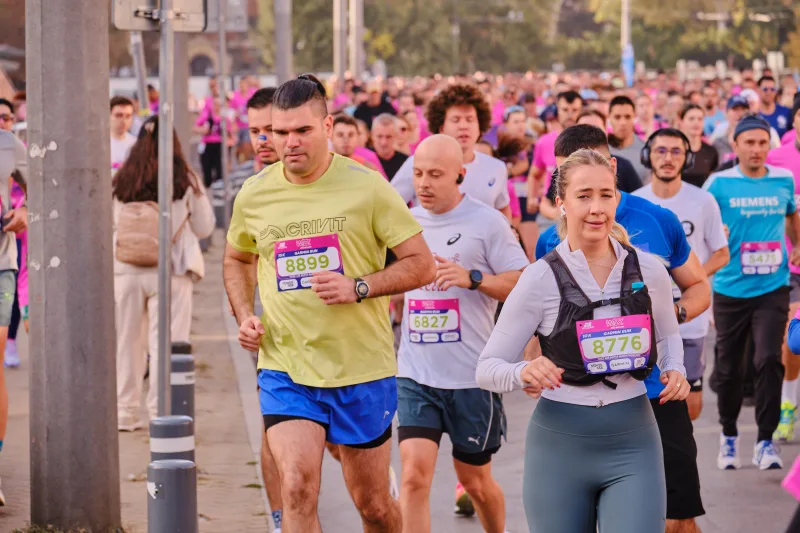 A runner in lime green beside a woman in a pale vest and headphones.