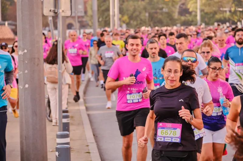 A runner in a black shirt smiling as she approaches the camera.