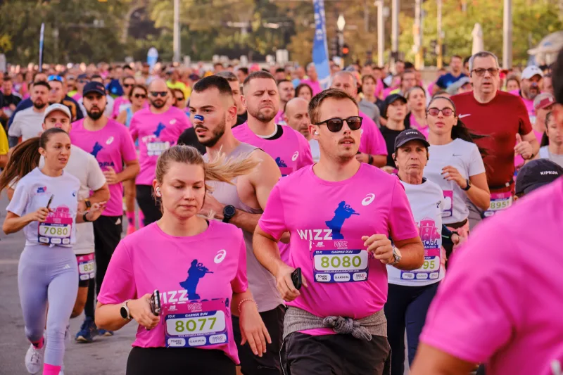 Two runners in pink shirts and sunglasses moving together through the field.