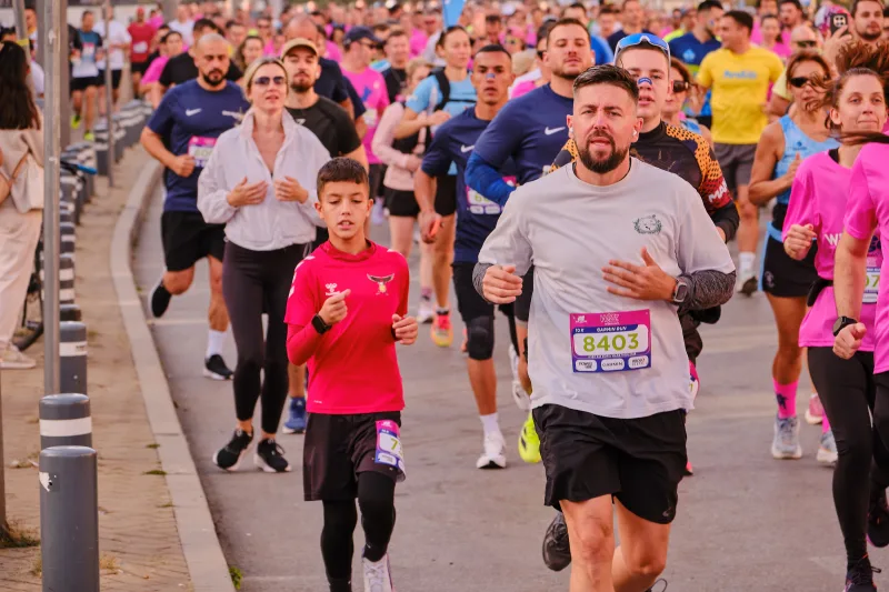 A young participant running beside a man in a grey shirt.