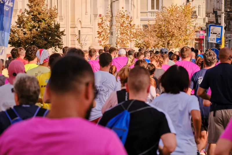 A view from behind the runners towards sunlit buildings and autumn trees.