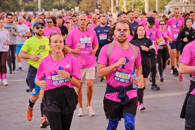 Two runners in pink shirts moving side by side through the field.