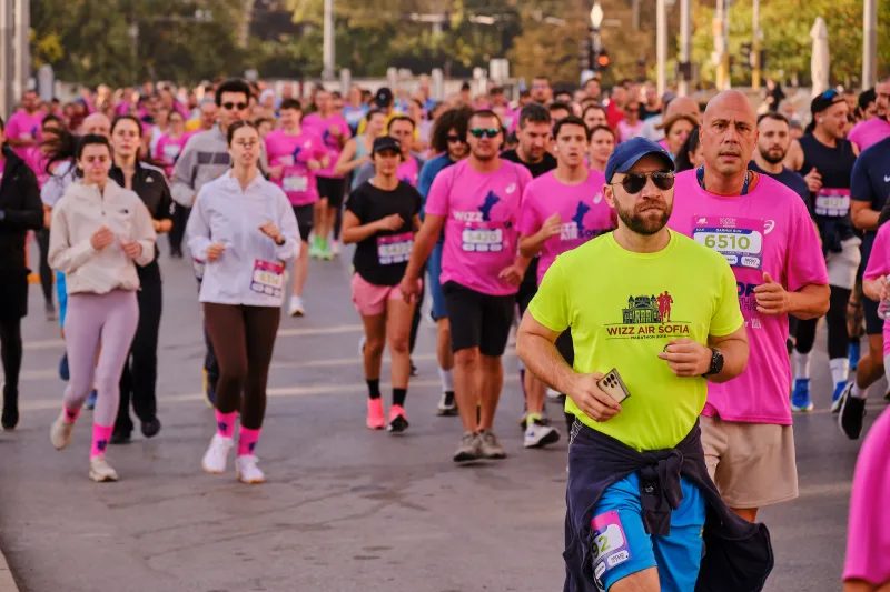 A runner in a lime green shirt and blue cap approaching down the road.