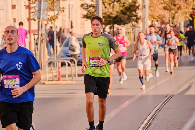 A runner in lime green and black approaching beside the tram tracks.