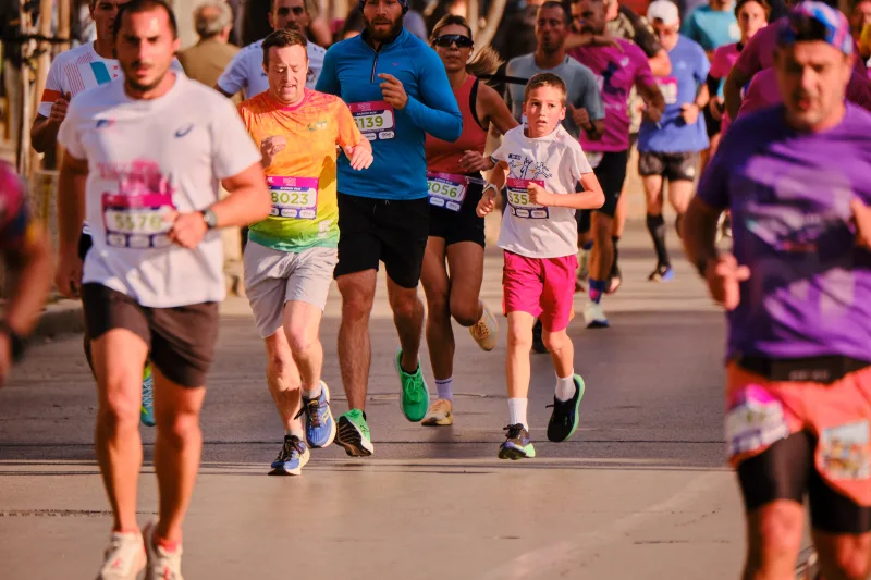 A young participant in red shorts running among adults.