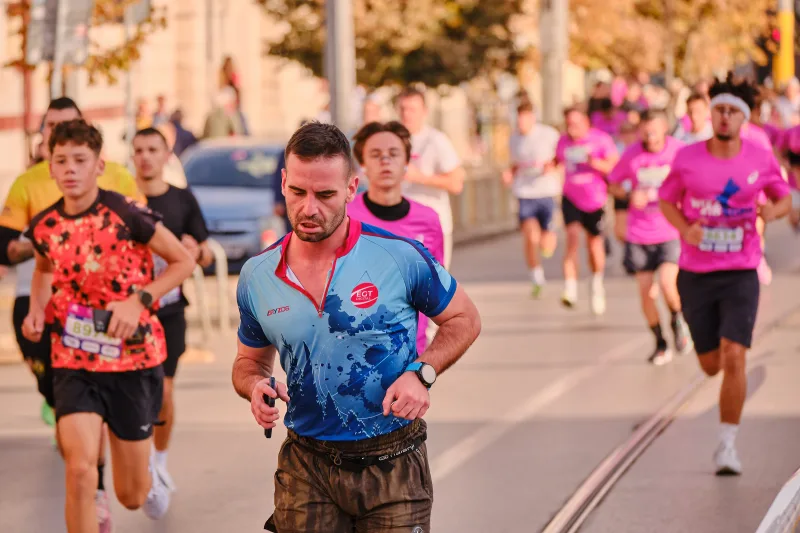 A runner in a patterned blue shirt with a jacket tied around his waist.