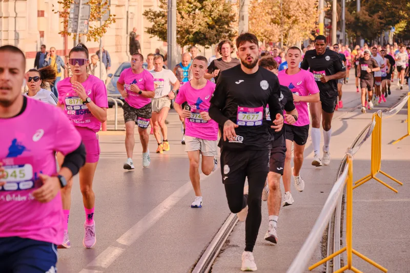 A runner in black approaching beside the yellow race barriers.