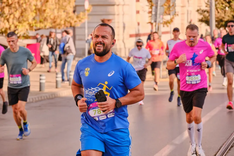 A smiling runner in a blue shirt and matching shorts.
