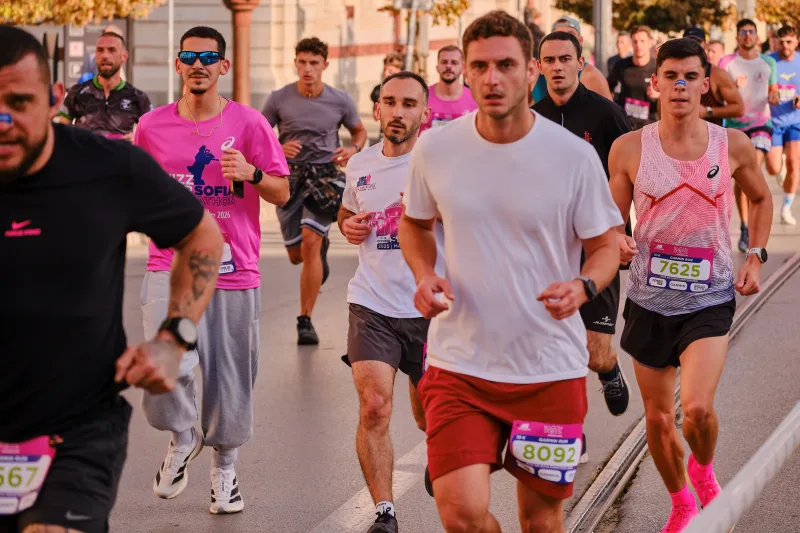 A runner in a pale grey shirt and headphones moving through the field.
