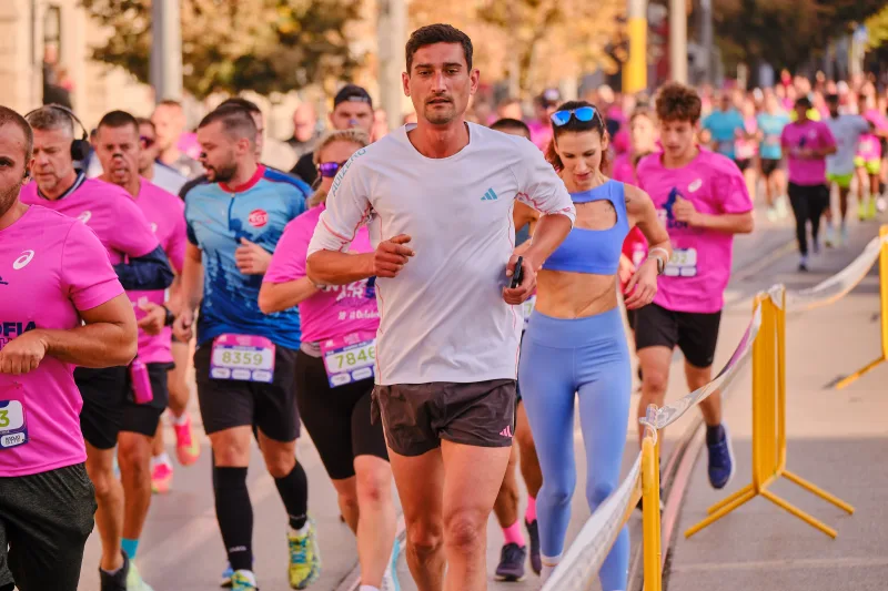 A runner in a white shirt alongside a woman wearing blue.