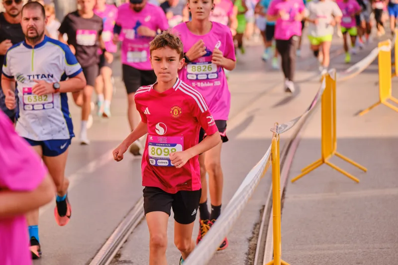 A young participant in red running beside the tram tracks.
