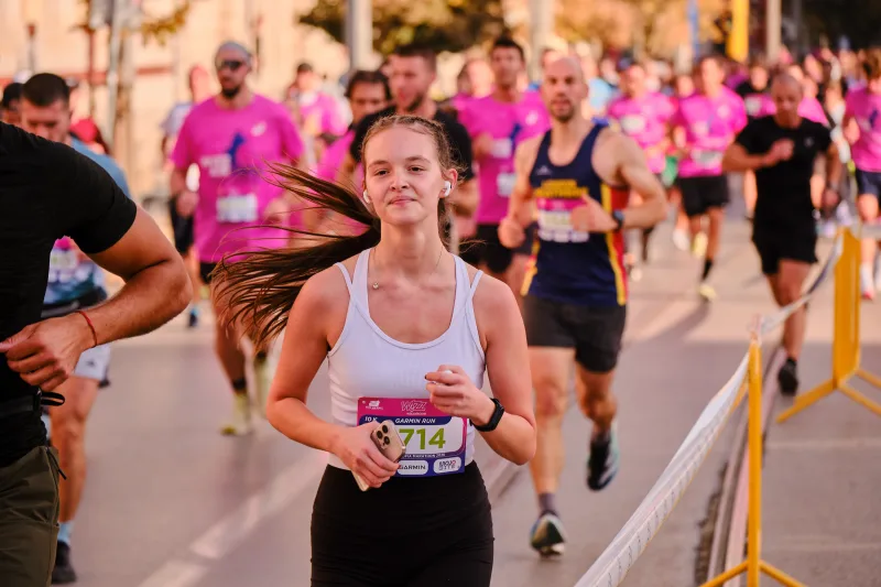 A woman in a white sleeveless top running with her hair flying behind her.
