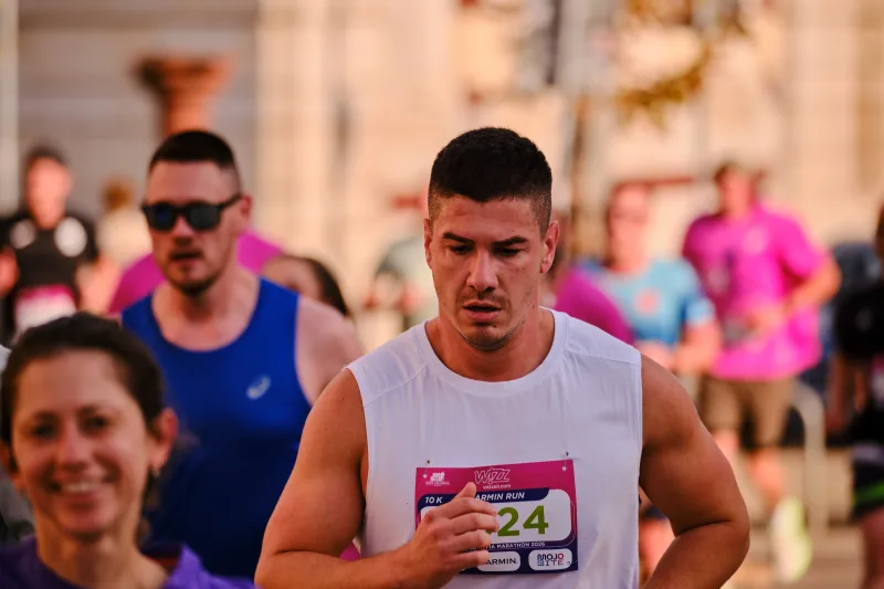 A close view of a runner in a pale sleeveless top.