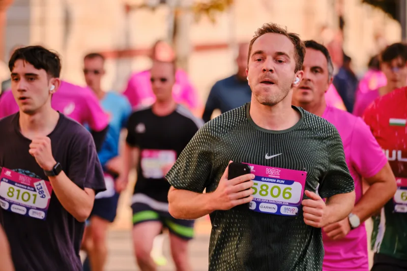 A runner in dark green approaching among participants in pink.