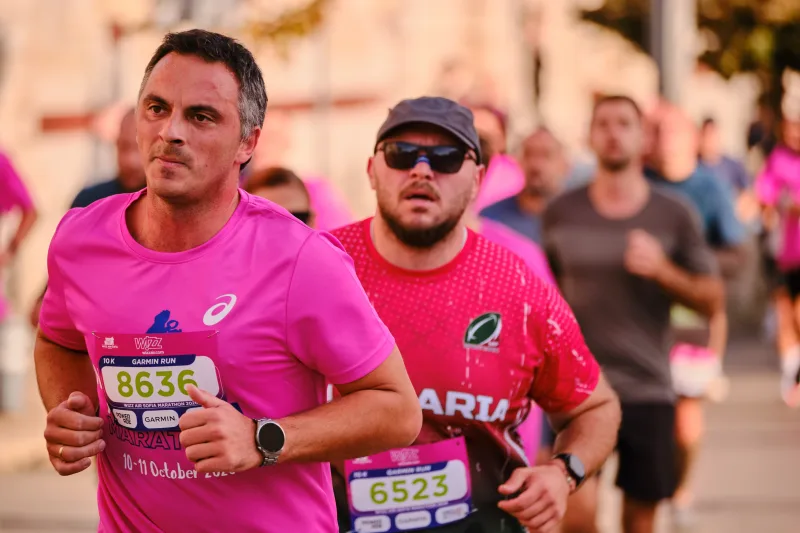 Two runners in pink shirts running together through the field.