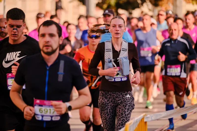 A runner in navy approaching ahead of a woman wearing a backpack.