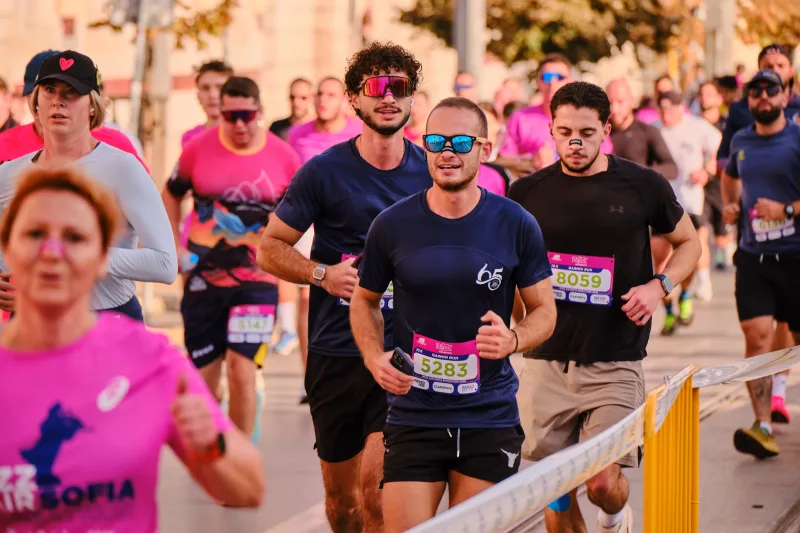 A smiling runner in a dark shirt moving through the crowd.