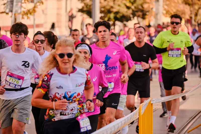 A woman in a colourful pale shirt and sunglasses among runners in pink.