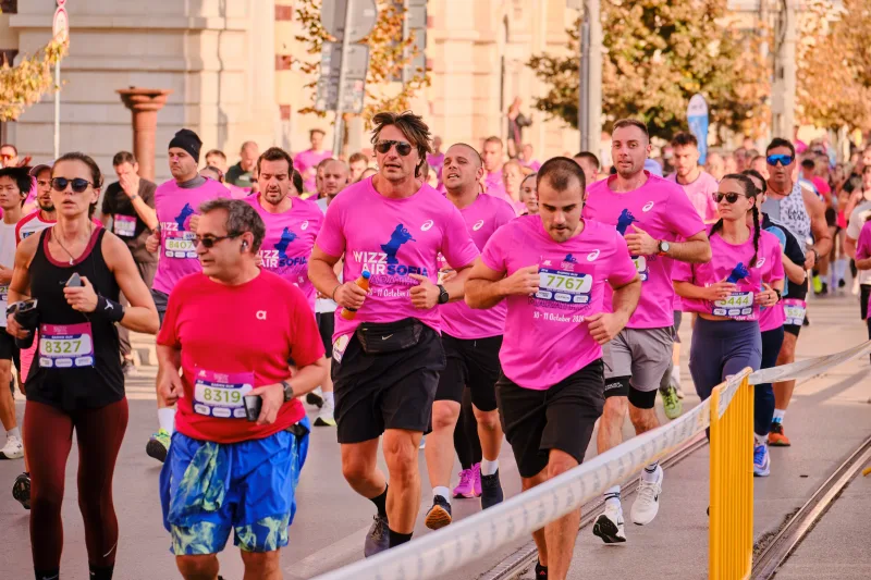 A runner in a red shirt and blue shorts approaching the camera.