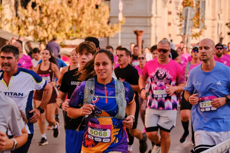 A runner wearing a blue hydration pack over a purple top.
