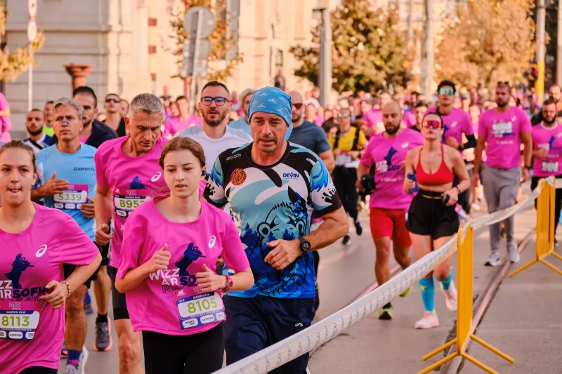 A young participant in pink beside a runner in a patterned blue shirt.